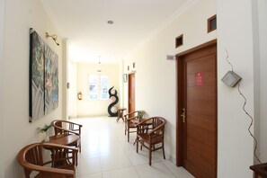 A hallway with wooden chairs, a wooden door, and a wall-mounted sign. - Collection O Jalan Malioboro Near Lempuyangan Stat (Yogyakarta)