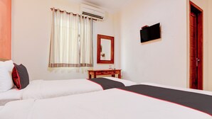 Una camera d'albergo con due letti, un comodino in legno, uno specchio e una televisione.