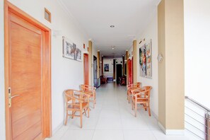 A hallway with wooden doors, chairs, and artwork on the walls. - Collection O Jalan Malioboro Near Lempuyangan Stat (Yogyakarta)