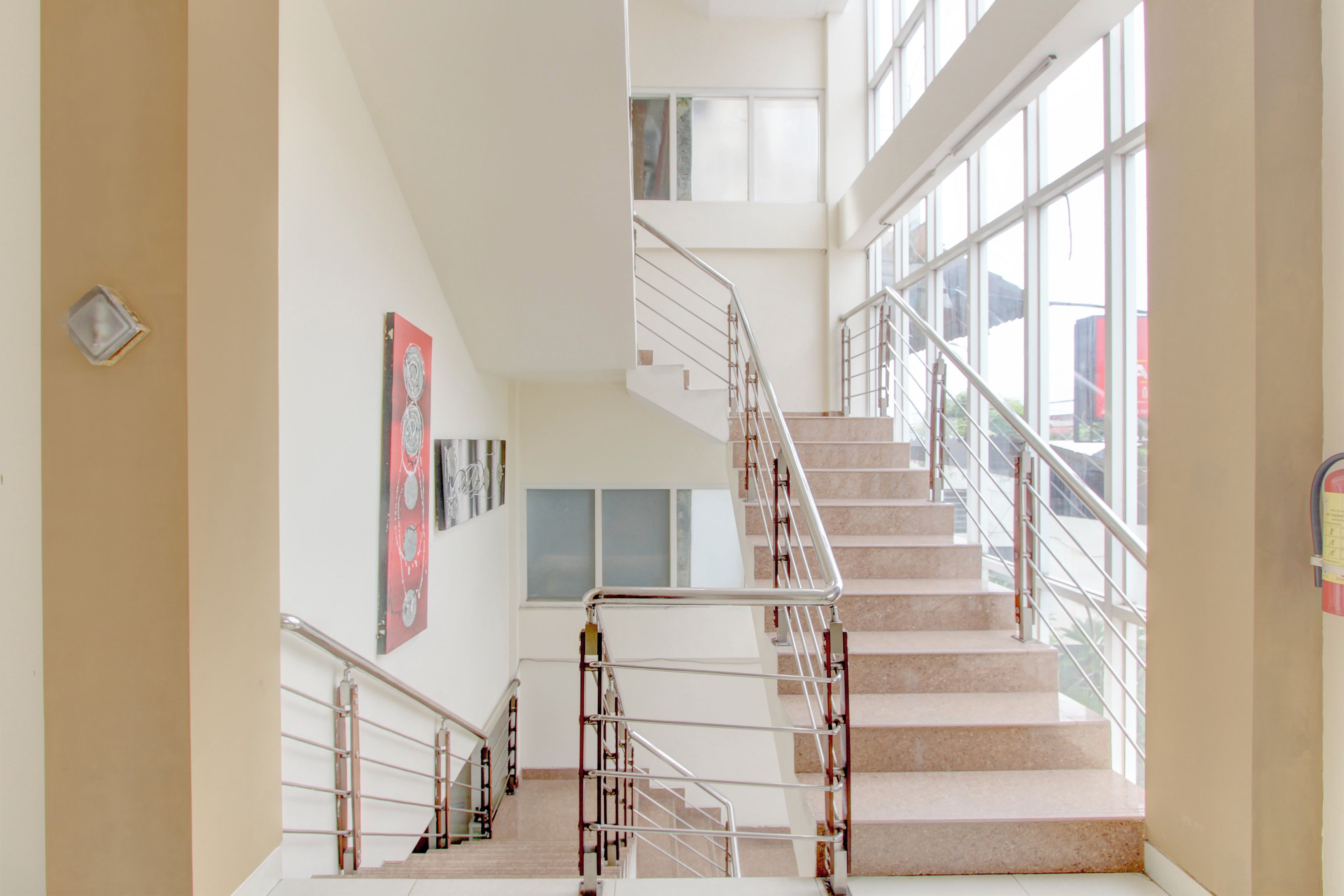 Ein mehrgeschossiges Interieur mit einer zentralen Treppe, großen Fenstern und einer an der Wand befestigten Uhr.