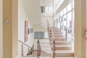 A multi-level interior with a central staircase, large windows, and a wall-mounted clock. - Collection O Jalan Malioboro Near Lempuyangan Stat (Yogyakarta)