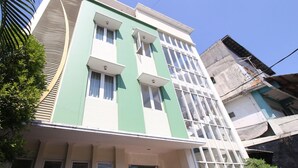 Un edificio a più piani con facciata verde, diverse finestre e un ingresso ben visibile.