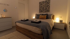 Une chambre à coucher avec un lit en bois, une table de chevet avec une lampe et une œuvre d’art accrochée au mur.