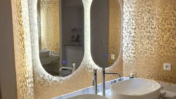 A bathroom with two round sinks, a large mirror, and a textured wall.