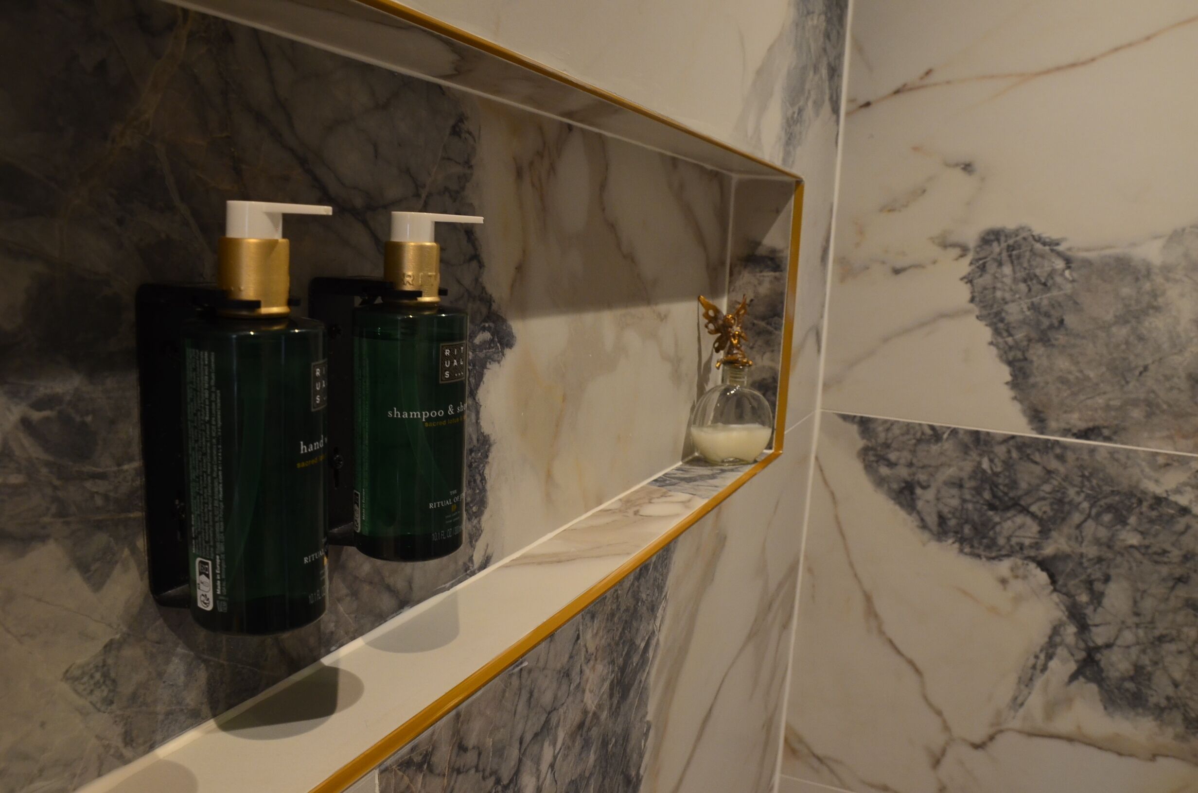 Un mobile bagno con ripiani in marmo e due flaconi di shampoo.
