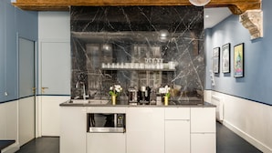 A modern kitchen with a marble backsplash, stainless steel appliances, and a central island. - Merveil Luxury Suite - Saint Denis I (Paris)