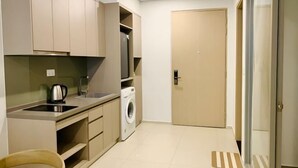 A compact kitchen with a washing machine, a kettle, and a sink. - 2 Bedroom Luxury Condotel - The Song Vung Tau (Vung Tau)