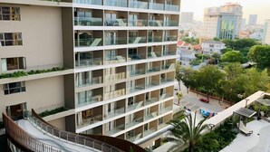 A multi-story hotel with balconies, a curved walkway, and a view of the surrounding cityscape. - 2 Bedroom Luxury Condotel - The Song Vung Tau (Vung Tau)