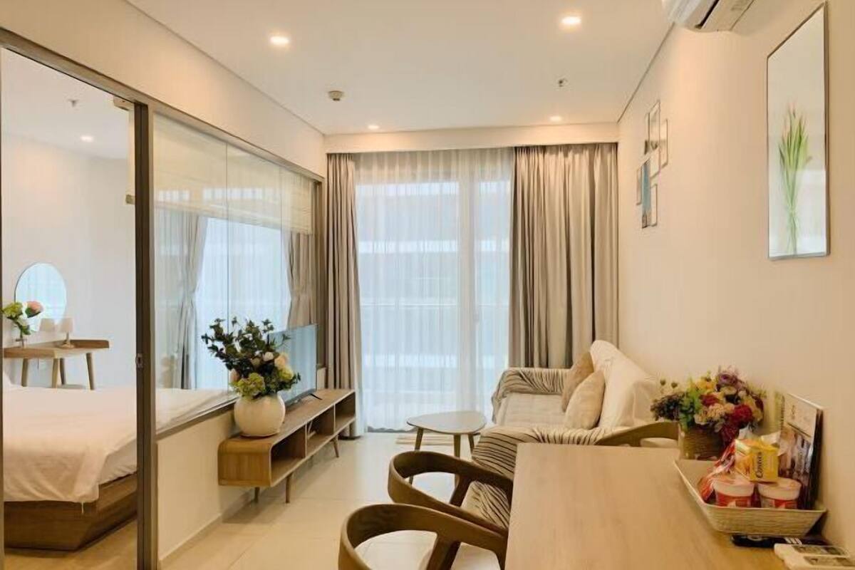 Ein modernes Hotelzimmer mit Bett, Fernseher, Esstisch und einer Couch.