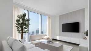A modern living room with a large window, a flat-screen TV mounted on the wall, and a minimalist design.