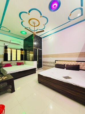 A modern bedroom with two beds, a ceiling fan, and a large mirror. - Royal Guest House (Ayodhya)