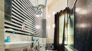 Ein Badezimmer mit Wand in Schwarz-Weiß-Fliesen, einem weißen Waschbecken, einer Toilette und einem roten Eimer.