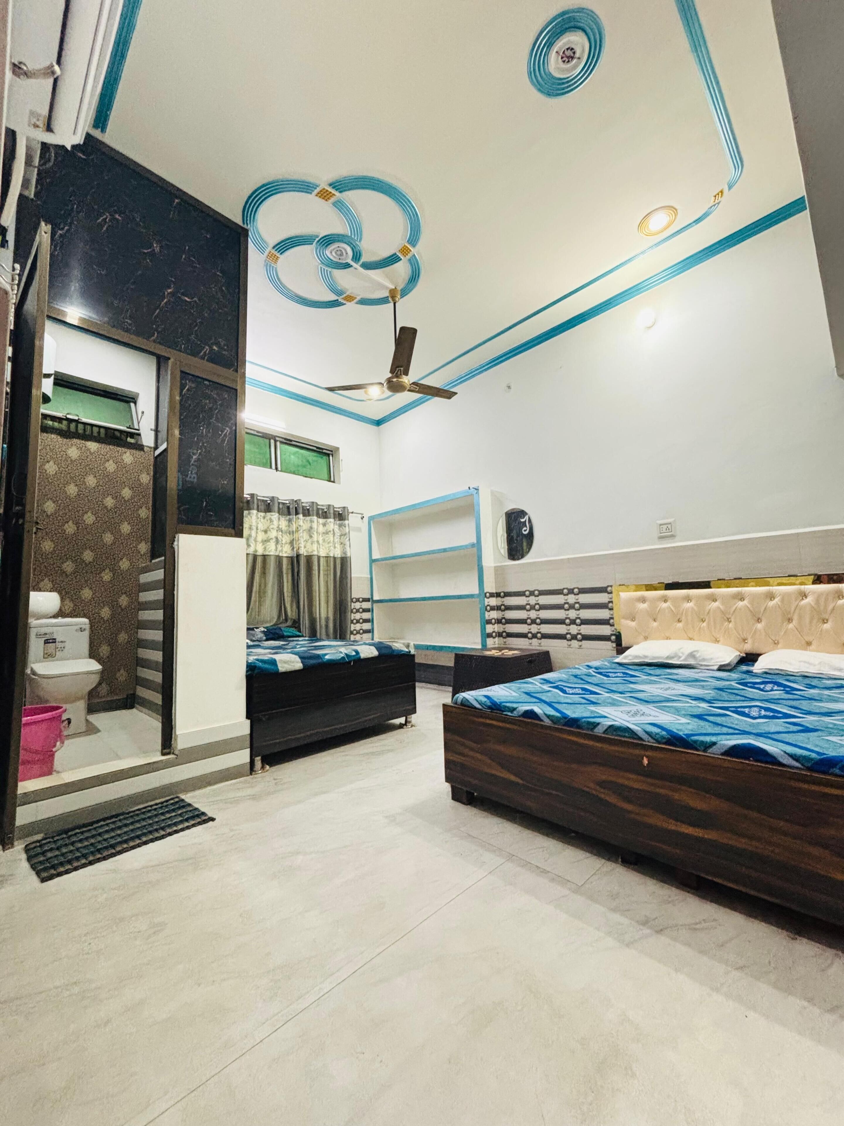 A bedroom with two beds, a ceiling fan, and a bathroom with a toilet and sink.