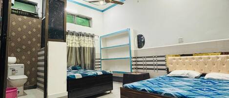 A bedroom with two beds, a ceiling fan, and a bathroom with a toilet and sink.