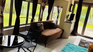 Un salon avec un canapé marron, une petite table ronde et un tapis de couleur turquoise.