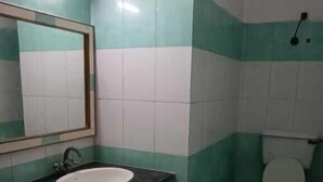 A bathroom with a sink, mirror, and toilet. - Hotel Swaagat (Agra)