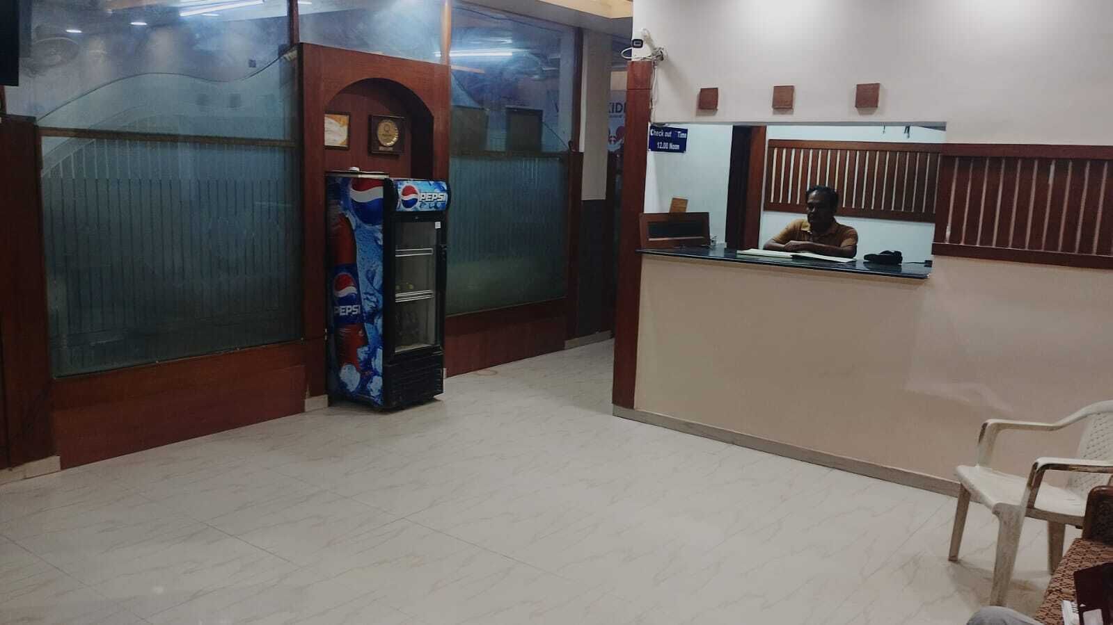 Un espace d’accueil comprenant un distributeur automatique de boissons Pepsi, un comptoir de réception et un espace d’attente avec un siège.