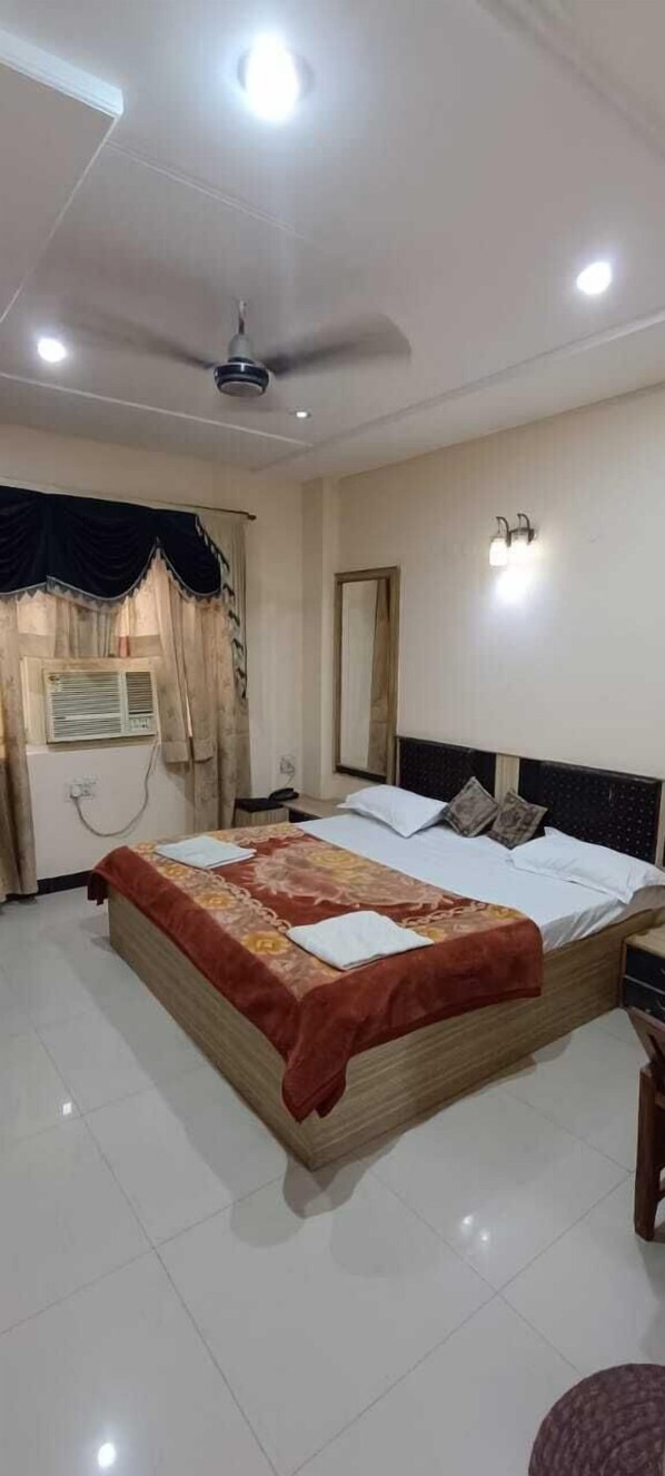 A bedroom with a bed, a ceiling fan, a window with curtains, and a wall-mounted light fixture.