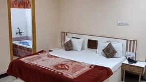 A bedroom with a bed, bedside table, and a nightstand. - Hotel Swaagat (Agra)