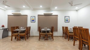A conference room with wooden tables and chairs, air conditioning units, and ceiling fans. - Treebo Flora Embassy (Chennai)