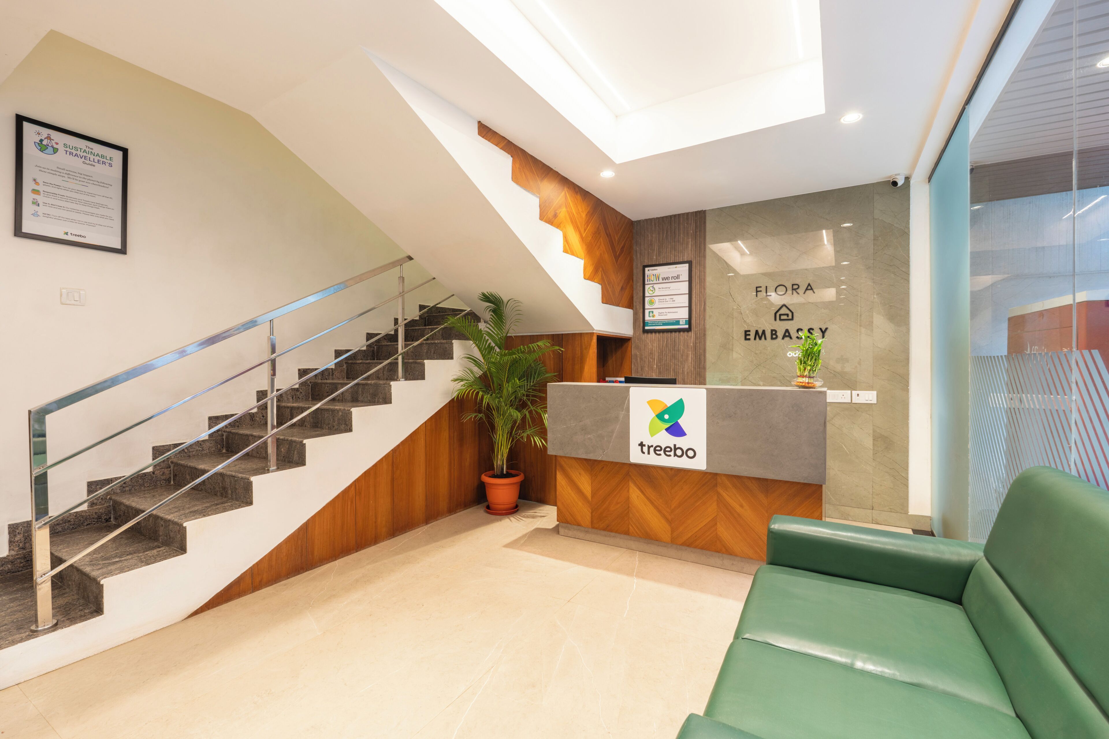 Un espace d’accueil comprenant un escalier, un comptoir de réception et un coin salon agrémenté de plantes vertes.