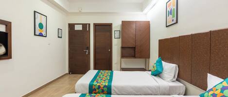 Habitación de hotel con dos camas, cabecera de madera y corredor de cama colorido.