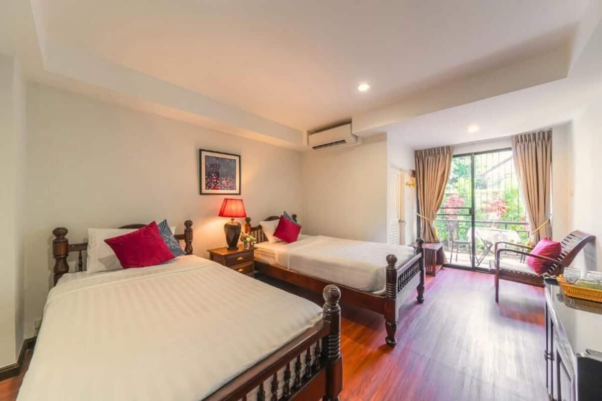 Habitación de hotel con dos camas, un balcón y vistas al exterior.