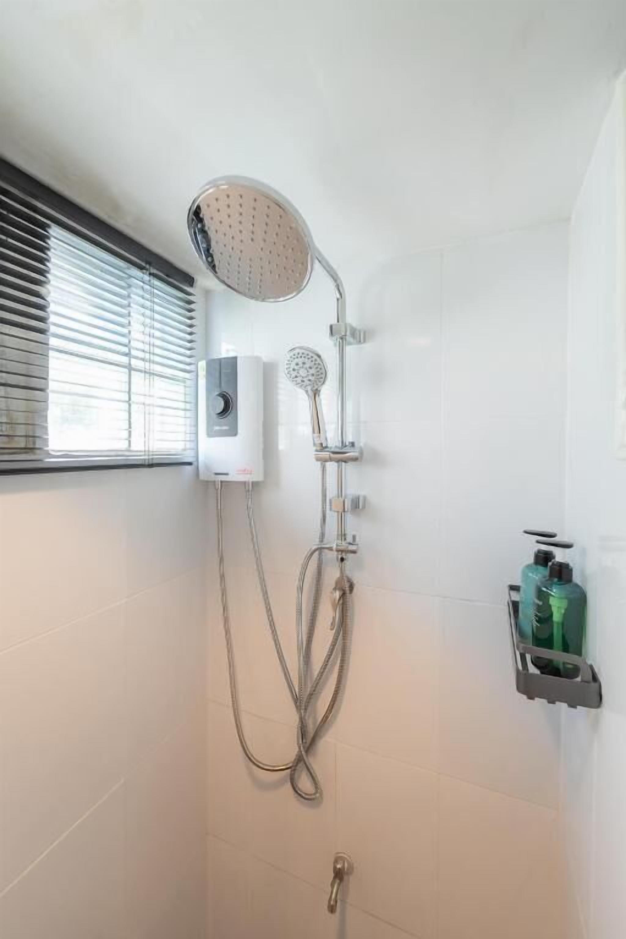 A shower with a handheld showerhead, a wall-mounted control panel, and a towel rack with bottles.