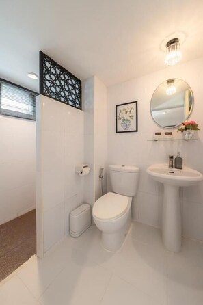 Un baño moderno con inodoro, lavamanos y ducha.