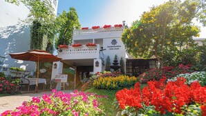 A building with a sign reading "Rachamanka Flora House" surrounded by vibrant flower beds. - Rachamankha Flora House Chiang Mai (Chiang Mai)