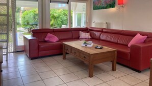 A red leather sofa, a wooden coffee table, and a painting on the wall. - 6 pers - Modern holiday home with garden, close the Lauwersmeer (Eanjum)