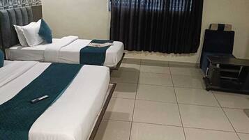 A hotel room with two beds, a small table, a chair, and a trash bin.