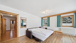 A modern bedroom with a bed, a small table, and a view of a snowy landscape through a window. - Apartment in a quiet location in Mittersill (Mittersill)
