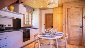 Una cocina moderna con armarios blancos, una estufa y un comedor con una mesa redonda para cuatro.