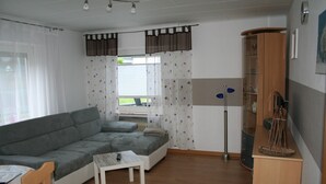 A living room with a grey sofa, a small white table, and a floor lamp. - Apartment 'Sammet' with Shared Terrace, Communal Garden and Wi-Fi (Brilon)