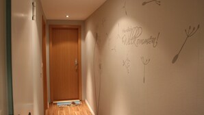 A hallway with a wooden door, a wall with doodles, and a small rug on the floor. - Apartment 'Sammet' with Shared Terrace, Communal Garden and Wi-Fi (Brilon)
