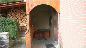 An outdoor entrance with a wooden archway, a stone wall, a small table, and a door leading inside. - Apartment 'Sammet' with Shared Terrace, Communal Garden and Wi-Fi (Brilon)