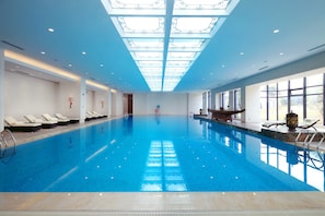 An indoor swimming pool with clear blue water, a skylight ceiling, and sunlit windows. - Yingbin Hotel (Dongguan)
