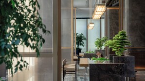 Un vestíbulo moderno con mostrador de recepción, zona de estar y plantas en macetas.