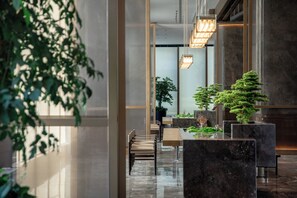 A modern lobby with a reception desk, seating area, and potted plants. - Yingbin Hotel (Dongguan)