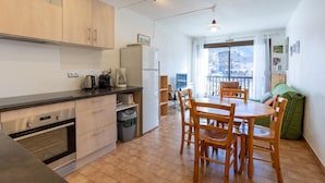 Una cuina moderna amb armaris de fusta, un forn encastrat i zona de menjador amb taula i cadires de fusta.
