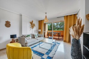 Un salon moderne avec un canapé, une table basse, un fauteuil jaune et des plantes décoratives.