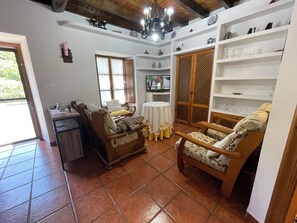 Un salon comprenant un canapé, des fauteuils, un téléviseur et un meuble en bois.