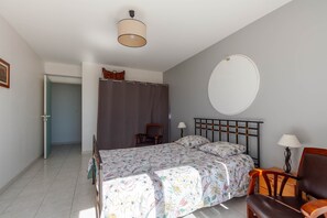A bedroom with a bed, a chair, a lamp, a shower curtain, and a door.