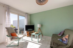 Un salon avec un téléviseur, une table, une chaise et un canapé.