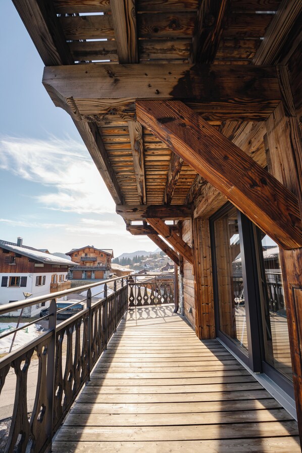 Un balcone in legno con vista su edifici e montagne.