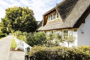 A traditional house with a thatched roof, white walls, and a wooden window frame.