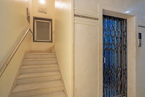A staircase with a handrail, a door with a metal grille, and a wall-mounted sign. - Itsy Hotels M (Vijayawada)