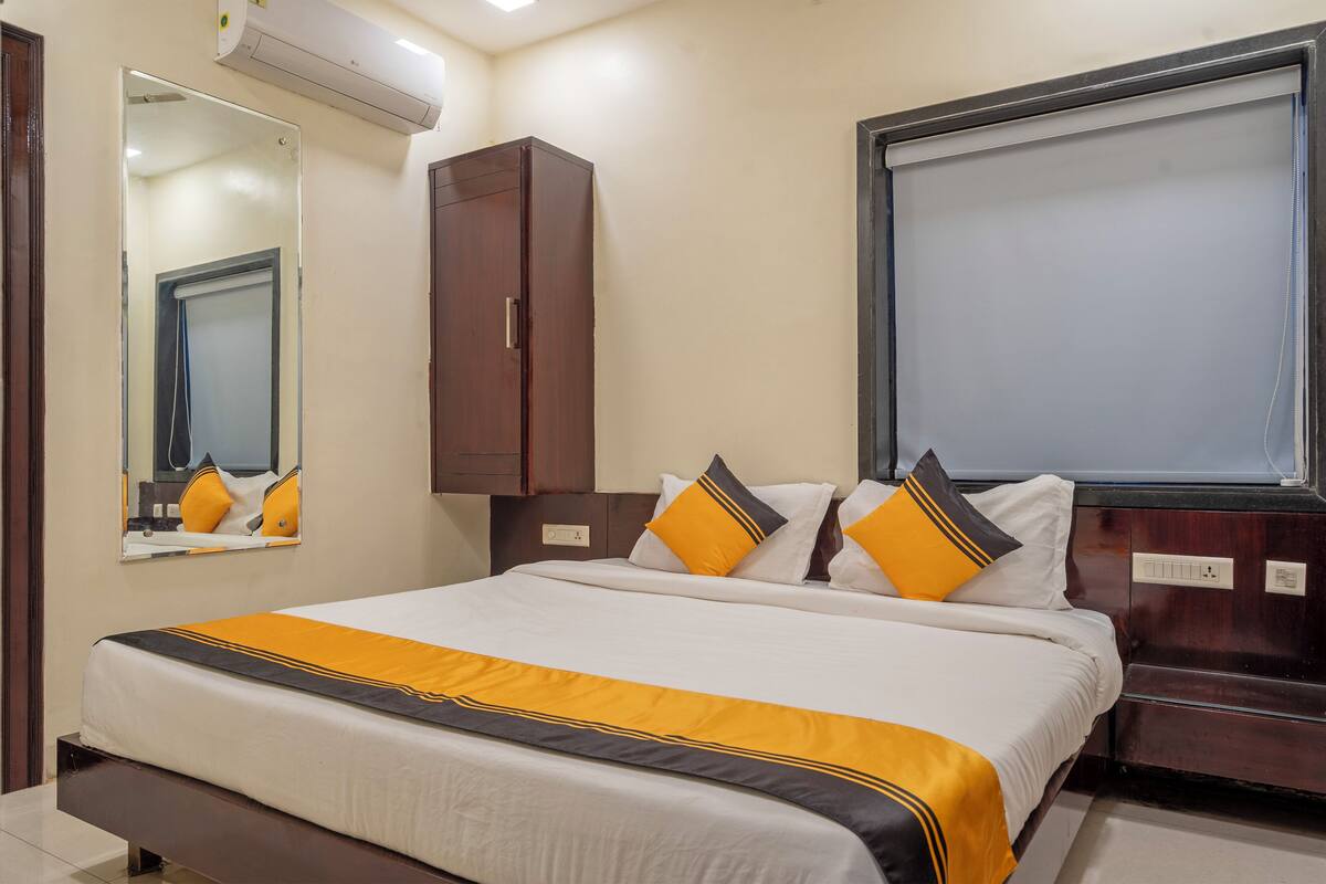 A hotel room with a bed, a wardrobe, a mirror, and a window.