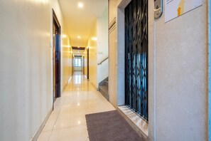 A hotel hallway with a carpeted floor, a staircase, and a metal gate. - Itsy Hotels M (Vijayawada)